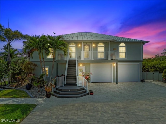 beach home with a garage, stucco siding, a porch, stairway, and metal roof