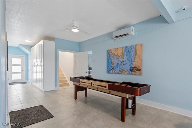 rec room featuring light tile patterned floors, baseboards, ceiling fan, and a wall mounted air conditioner