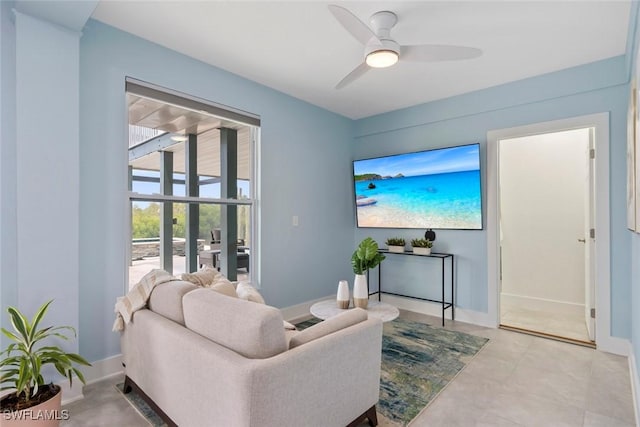 living area with ceiling fan and baseboards