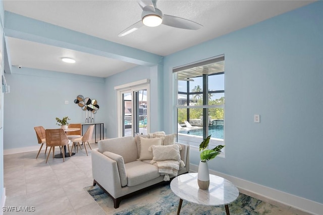 living area with baseboards and a ceiling fan