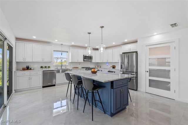 kitchen with white cabinets, appliances with stainless steel finishes, a sink, a kitchen island, and visible vents