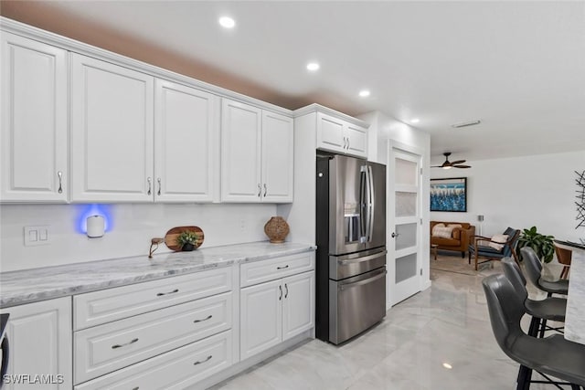 kitchen featuring marble finish floor, light stone countertops, white cabinetry, stainless steel fridge with ice dispenser, and a ceiling fan