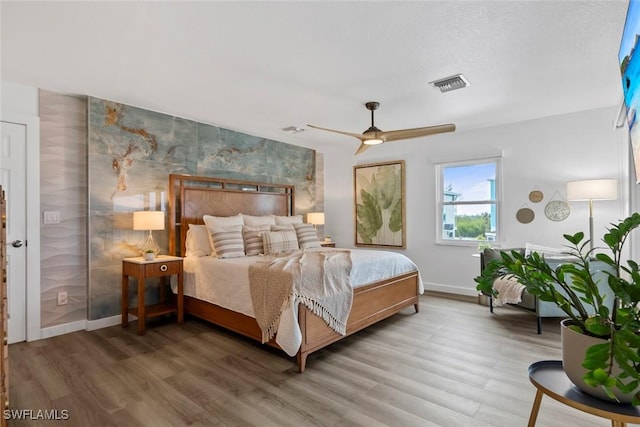 bedroom featuring visible vents, baseboards, ceiling fan, and wood finished floors