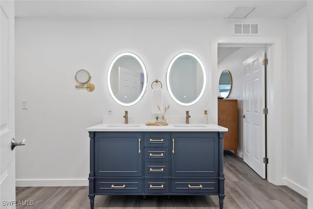 bathroom featuring visible vents, a sink, and wood finished floors