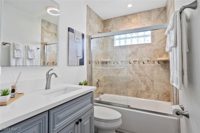 bathroom featuring vanity, combined bath / shower with glass door, and toilet