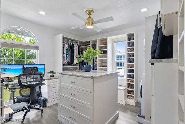 interior space featuring light wood-style floors, a ceiling fan, and stacked washer / dryer