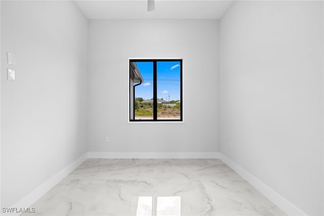 spare room with baseboards, ceiling fan, and marble finish floor