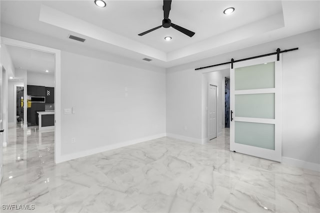 spare room featuring marble finish floor, ceiling fan, recessed lighting, a barn door, and a tray ceiling