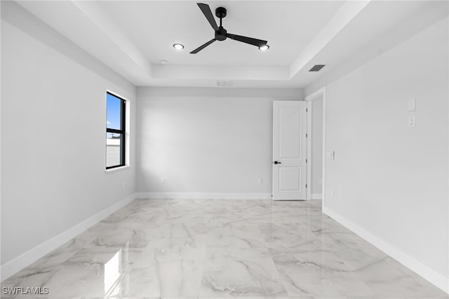 empty room featuring visible vents, a ceiling fan, a tray ceiling, and marble finish floor