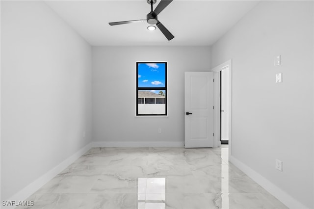 empty room with baseboards, a ceiling fan, and marble finish floor