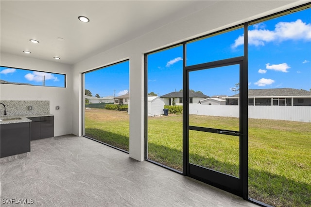 unfurnished sunroom featuring a residential view, a sink, and an outdoor kitchen
