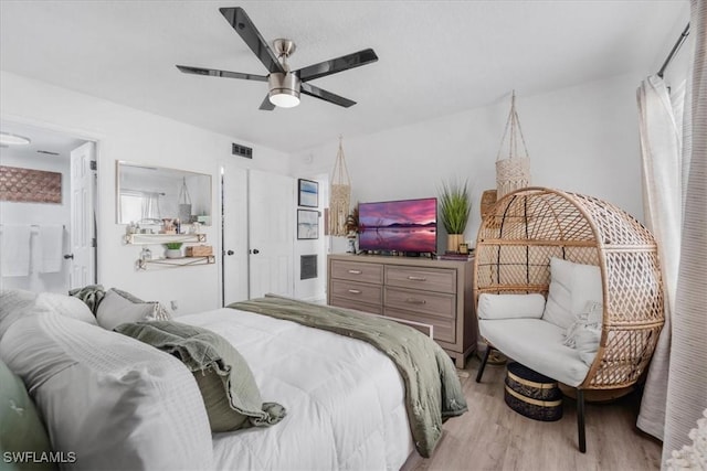 bedroom featuring light wood-type flooring, ceiling fan, and ensuite bath