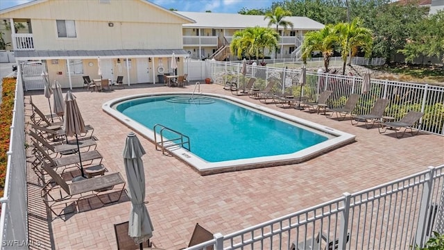 community pool with a patio and fence