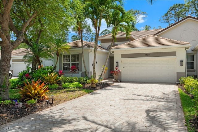 view of front facade featuring a garage, stucco siding, driveway, and a tile roof
