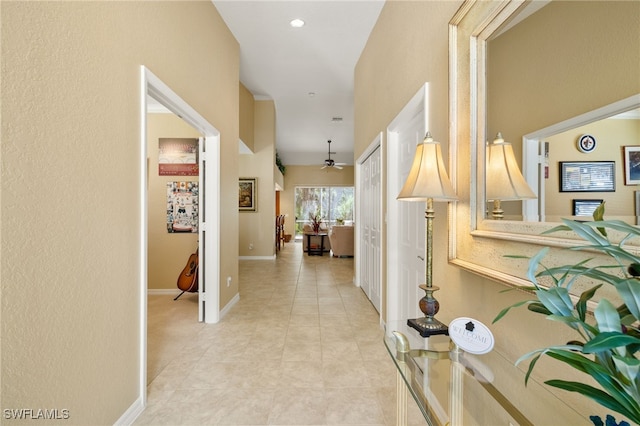 hallway featuring baseboards, recessed lighting, and light tile patterned flooring