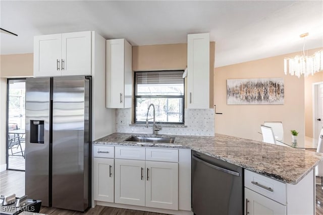 919 SE 16th St, Cape Coral, FL 33990 - kitchen with stainless steel appliances, a sink, a peninsula, decorative backsplash, and white cabinetry