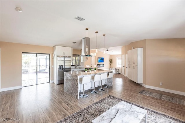 919 SE 16th St, Cape Coral, FL 33990 - kitchen with stainless steel fridge with ice dispenser, a center island, range hood, wood finished floors, and a kitchen breakfast bar