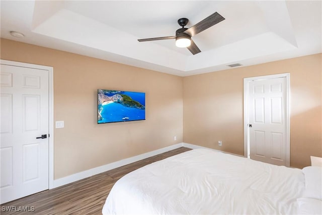 919 SE 16th St, Cape Coral, FL 33990 - bedroom featuring a tray ceiling, wood finished floors, baseboards, and a ceiling fan