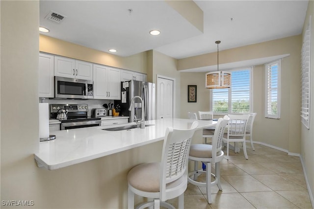 7505 Stoneybrook Dr Unit 746, Naples, FL 34112 - kitchen with appliances with stainless steel finishes, a sink, a kitchen breakfast bar, decorative light fixtures, and visible vents