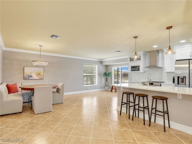 11526 Forest Mere Dr, Bonita Springs, FL 34135 - kitchen with light tile patterned flooring, a kitchen breakfast bar, wall chimney exhaust hood, light countertops, and appliances with stainless steel finishes