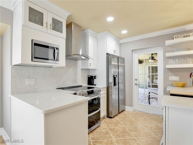 11526 Forest Mere Dr, Bonita Springs, FL 34135 - kitchen with stainless steel appliances, wall chimney range hood, crown molding, white cabinetry, and backsplash