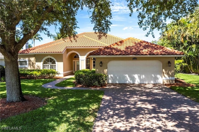 mediterranean / spanish-style house with a front lawn, stucco siding, a tiled roof, an attached garage, and driveway