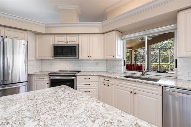 kitchen with tasteful backsplash, a sink, ornamental molding, stainless steel appliances, and white cabinetry