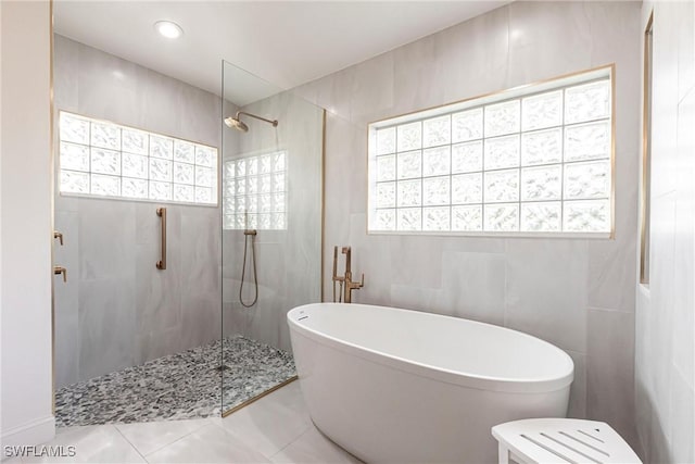 full bathroom featuring walk in shower, a freestanding bath, and tile walls