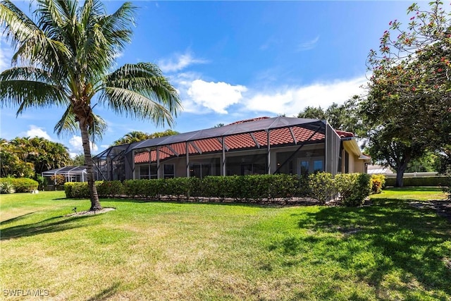 back of house featuring a lawn and a lanai