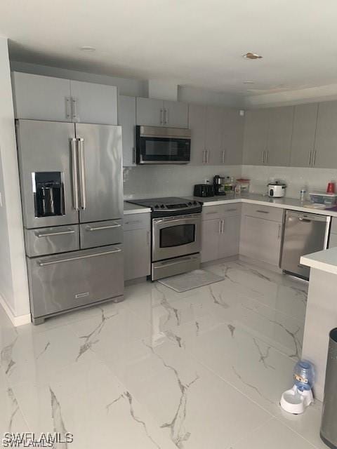 kitchen with stainless steel appliances, gray cabinets, and light marble finish flooring