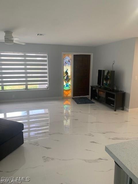 living area with marble look tiles and a ceiling fan