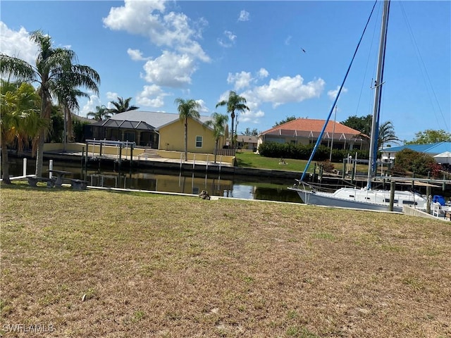 view of grassy yard featuring a water view and a boat dock