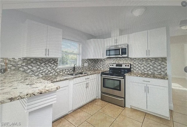 kitchen featuring backsplash, stainless steel appliances, light stone countertops, and a sink