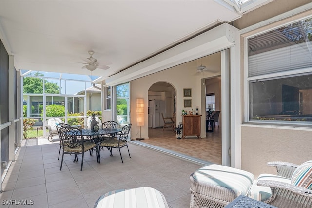 sunroom / solarium featuring outdoor dining space, arched walkways, and a ceiling fan