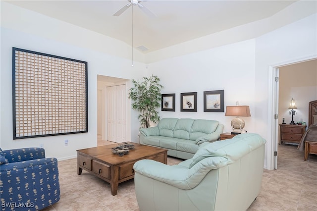 living area with a ceiling fan, light tile patterned floors, and a towering ceiling
