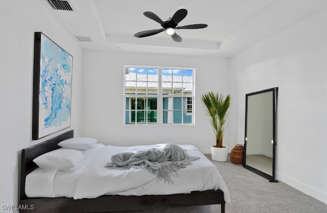 bedroom featuring a tray ceiling, visible vents, and carpet
