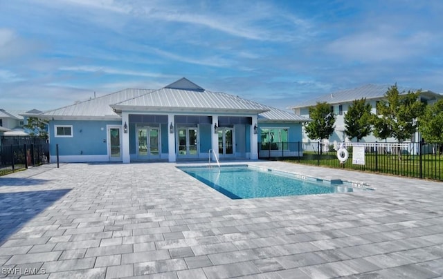 community pool with french doors, fence, and a patio area