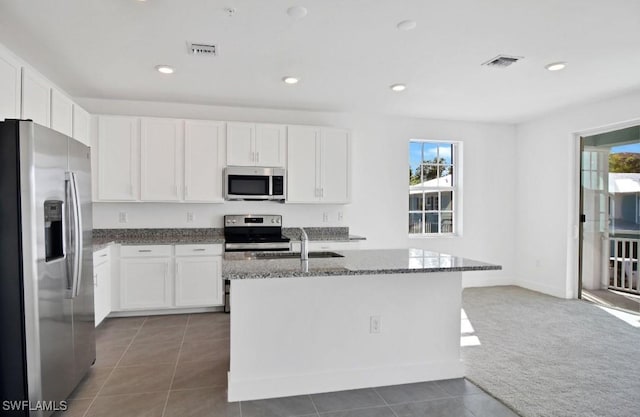 kitchen featuring dark stone counters, white cabinets, stainless steel appliances, and visible vents