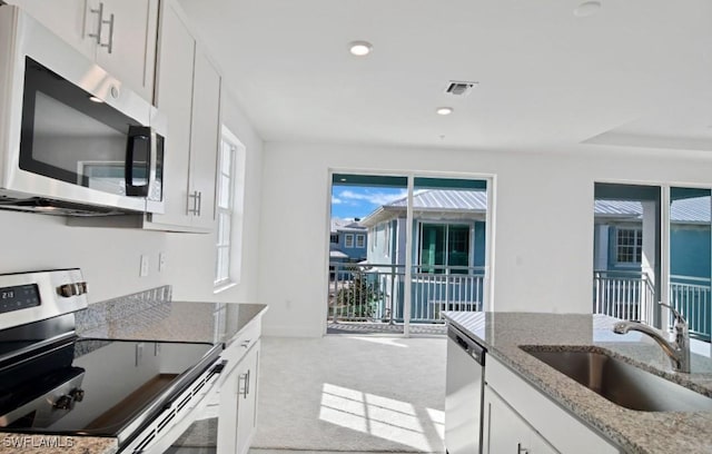 kitchen with visible vents, a sink, light stone counters, stainless steel appliances, and white cabinetry