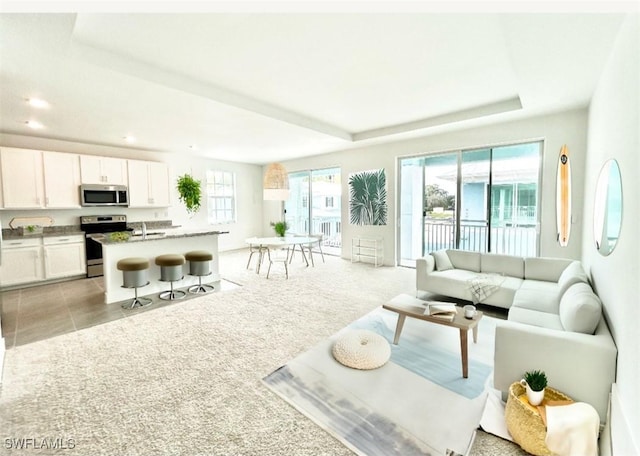 living room featuring a healthy amount of sunlight, a tray ceiling, recessed lighting, and light colored carpet