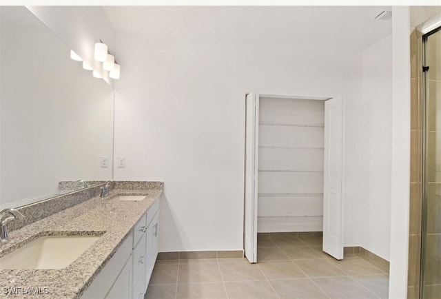 full bath featuring baseboards, tile patterned floors, a spacious closet, and a sink
