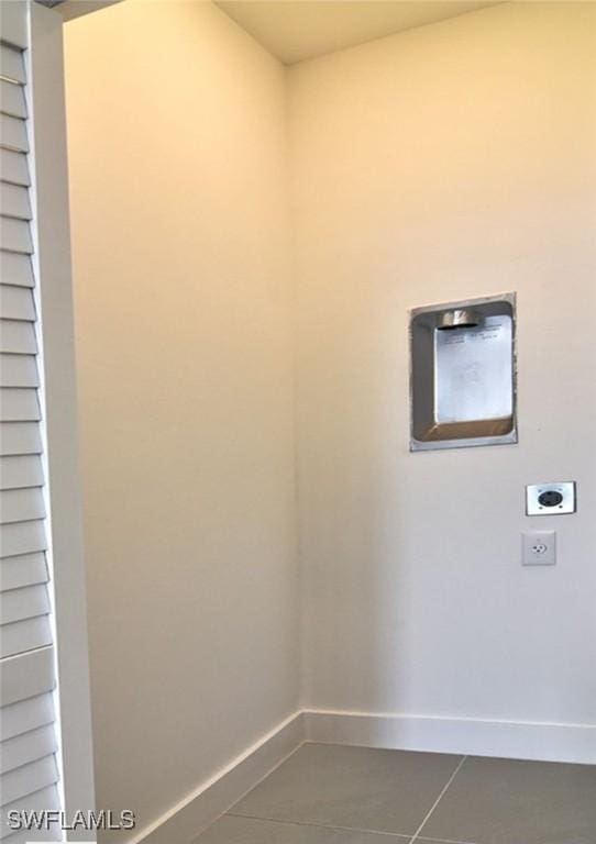 clothes washing area featuring dark tile patterned flooring, electric dryer hookup, baseboards, and laundry area