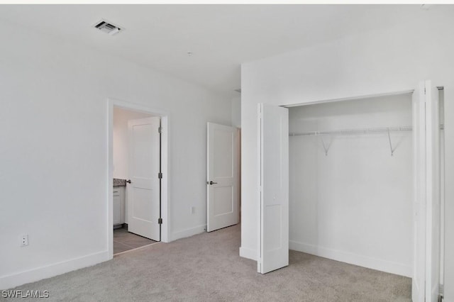 unfurnished bedroom with visible vents, a closet, baseboards, connected bathroom, and carpet flooring