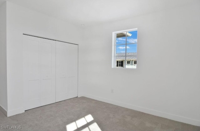 unfurnished bedroom with baseboards, carpet, and a closet