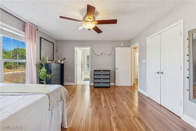 239 Leawood Cir, Naples, FL 34104 - bedroom with light wood finished floors, a textured ceiling, a closet, baseboards, and a ceiling fan