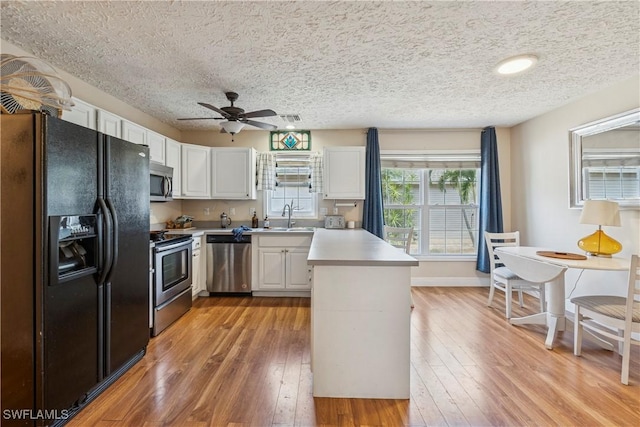 239 Leawood Cir, Naples, FL 34104 - kitchen with stainless steel appliances, a peninsula, a ceiling fan, light countertops, and light wood-style floors