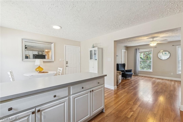 239 Leawood Cir, Naples, FL 34104 - kitchen with a textured ceiling, light wood-type flooring, baseboards, ceiling fan, and light countertops
