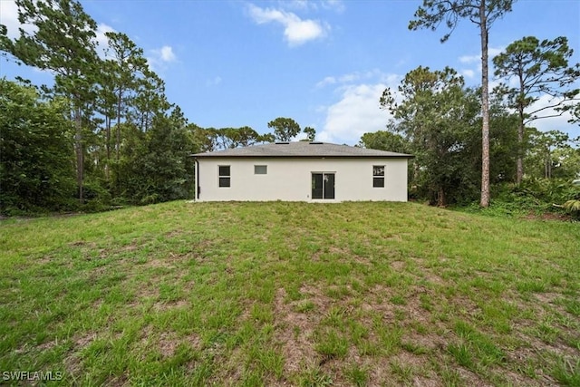 836 Clow St E, Lehigh Acres, FL 33974 - rear view of property featuring a yard and stucco siding