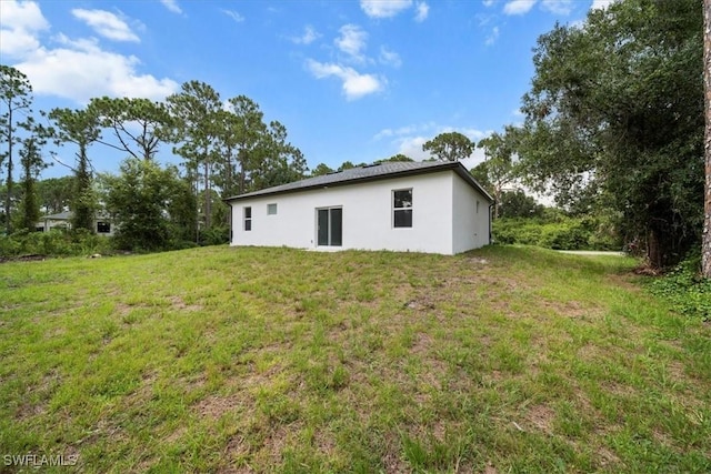 836 Clow St E, Lehigh Acres, FL 33974 - rear view of property featuring stucco siding and a lawn