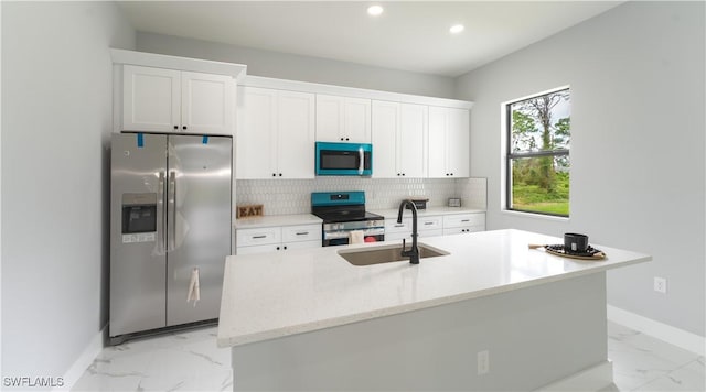 203 E 10th St, Lehigh Acres, FL 33972 - kitchen featuring stainless steel appliances, a sink, light marble finish floors, baseboards, and white cabinets